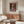 May include: colorful landscape poster with vibrant sunset sky and water reflection, displayed above wooden credenza in modern living room with cream walls, white sculptural chair, glass coffee table, and warm natural lighting creating soft shadows