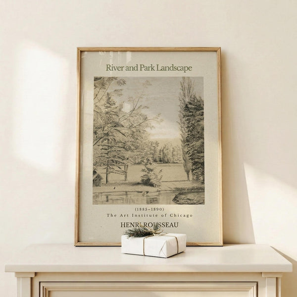 May include: Framed vintage botanical illustration print leaning against white wall on light wooden surface. Black and white etching shows tranquil park scene with trees, water, and small structure. Aged cream matting with text details below artwork. Small white wrapped gift box with natural twine and greenery sprig positioned in front. Soft natural lighting creates gentle shadows on minimalist display.