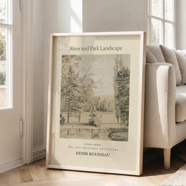 May include: Framed vintage-style poster featuring a sepia-toned landscape drawing with trees, water, and small structures. The print shows "River and Park Landscape" at top, dated 1885-1890, attributed to Henri Rousseau and The Art Institute of Chicago. Light wood frame leans against white wall next to beige upholstered chair on hardwood floor in bright, minimalist room with large windows.