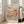 May include: Framed art print leaning against white wall next to beige sofa in bright living room. Abstract botanical illustration features coral, peach and cream colored mushrooms, flowers and organic shapes with polka dot patterns. Japanese text appears at bottom. Natural wood frame, approximately 2-3 feet tall, positioned on light wooden floor near windows with natural lighting.