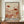 May include: Framed art print displayed on wooden sideboard featuring abstract botanical illustration in warm earth tones with red polka-dotted mushrooms, delicate flowers, and organic shapes in coral, beige, and rust colors. White ceramic vase and stacked books sit nearby. The poster has Japanese text at bottom and shows modern minimalist interior with cream walls and wood furniture.