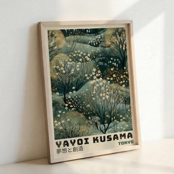 May include: Framed art print leaning against white wall showing abstract botanical illustration in muted green, sage, and cream tones with delicate flowering branches, dotted textures, and organic shapes. Light wooden frame surrounds artwork featuring "YAYOI KUSAMA TOKYO" text at bottom with Japanese characters below.