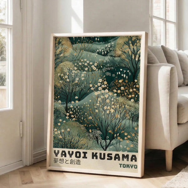 May include: Framed botanical art print leaning against white wall beside beige couch in bright living room. Artwork features layered green foliage patterns with cream flowers and dotted textures in nature-inspired design. Light wood frame, approximately 2-3 feet tall, positioned on light hardwood floors near large windows with natural sunlight streaming in.
