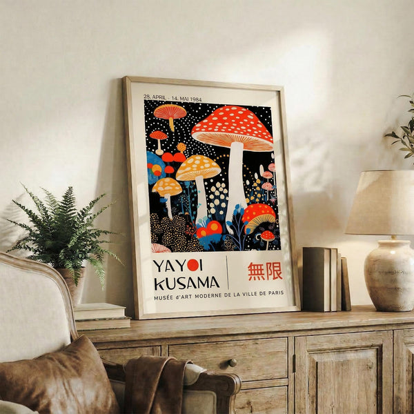 May include: Framed poster featuring colorful mushrooms with red and orange spotted caps against a black dotted background, displayed on a rustic wooden console table beside a fern plant, ceramic vase, and leather chair in a neutral-toned living room setting.