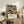 May include: Framed abstract art poster with swirling colorful patterns in purple, orange, and blue tones featuring polka dots and flowing organic shapes. Text reads "YAYOI KUSAMA" with Japanese characters and "MUSÉE d'ART MODERNE DE LA VILLE DE PARIS". Displayed on rustic wooden console table with books, ceramic vase, fern plant, and leather chair in warm neutral living room setting.