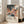 May include: Framed art print leaning against white wall next to beige sofa in bright living room. Artwork features whimsical desert landscape with colorful cacti, flowing abstract shapes in coral, teal, and yellow tones, polka dot patterns, and starry night sky. Text reads "YAYOI KUSAMA" with Japanese characters and "永遠に続く愛 MUSEE d'ART MODERNE DE LA VILLE DE PARIS" below the illustration.