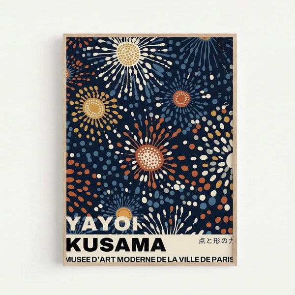 Framed art print featuring abstract burst patterns on navy blue background with radiating dots and rays in orange, yellow, white, and blue tones. Text reads "YAYOI KUSAMA" and "MUSEE D'ART MODERNE DE LA VILLE DE PARIS" with Japanese characters. Light wood frame mounted on white wall with soft shadows.