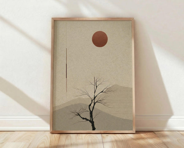 May include: A framed minimalist art print leaning against a white wall on light wooden flooring. The artwork features a bare black tree silhouette against beige textured background with layered mountain shapes and a rust-colored circular sun. Natural wood frame with visible grain. Soft shadows cast across the scene from window light.