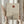 May include: Person in beige clothing holding framed minimalist artwork featuring a bare black tree silhouette against layered tan mountains with rust-colored sun above, displayed in light wood frame next to dried pampas grass in soft natural lighting near window with neutral curtains