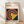 May include: Framed Bauhaus poster print in light wood frame, leaning against white wall on wooden floor. Features geometric design with colorful concentric circles in red, yellow, blue, and orange on dark blue background with yellow triangular shape. Modernist typography at top references the design school's history and locations.