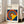 May include: Framed Bauhaus poster with geometric design featuring colorful concentric circles in red, yellow, blue, and white on navy background with yellow triangular shape. Light wood frame leaning against white wall next to beige sofa in bright living room with large windows and natural light casting shadows on wooden floor.
