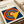 May include: Framed Bauhaus poster print featuring bold concentric circles in red, yellow, blue, and white on navy background with yellow triangular overlay. Modern minimalist design displayed in white matted frame on cream surface beside rolled papers, showcasing the geometric art movement's characteristic clean lines and primary color palette.