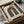 May include: Framed Bauhaus-inspired poster featuring a geometric arch design in dark green with concentric curved lines and an orange circle accent, displayed in black frame within cardboard packaging with protective tissue paper and wooden dowels on white surface