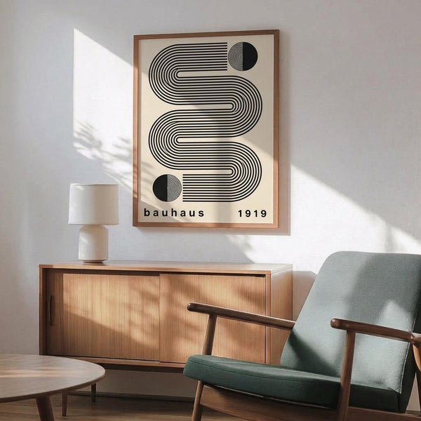 May include: Framed Bauhaus-inspired poster with black geometric wavy lines and circles on cream background, displayed above wooden sideboard in modern living room with mint green upholstered chair, white table lamp, and natural lighting casting shadows on white walls.