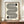 May include: Black and white geometric poster with flowing curved lines forming an S-like shape and two half-circles, text reading "bauhaus 1919" below, displayed in brown wooden frame on wooden sideboard next to white ceramic vase and books in cream-walled room with white trim molding.