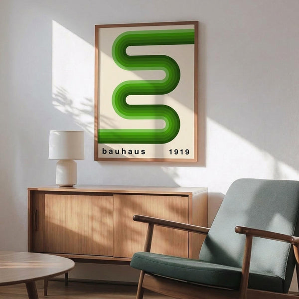 May include: Framed geometric poster with flowing green S-shaped ribbons on cream background, displayed above wooden sideboard with white lamp in modern living room setting. Green upholstered mid-century armchair with wooden frame sits nearby. Natural sunlight creates shadows on white wall, showcasing the minimalist Bauhaus-inspired design.