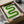 May include: Green geometric poster with curved serpentine design in gradient shades from light to dark green on cream background, displayed in black frame inside cardboard shipping box with protective padding, surrounded by white tissue paper and wooden dowels for packaging