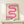May include: Framed poster with pink gradient ribbon design in wavy S-curve pattern against cream background, displayed on light wood console table next to small wrapped gift with greenery sprig. Thin natural wood frame with glass front, soft shadows on neutral wall behind.