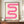 May include: A framed poster featuring a flowing pink ribbon design with gradient stripes creating an S-shaped curve on cream background, with "bauhaus 1919" text below. The brown wooden frame sits on a wooden sideboard next to a white ceramic vase and books, against beige paneled walls in an elegant interior setting.