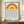 May include: A framed minimalist poster featuring an orange semicircle sun above blue wavy lines representing water, with "bauhaus 1919" text below. The artwork is displayed in a thin brown frame on a wooden shelf next to a small cream ceramic vase and white books against beige paneled walls.