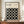May include: Framed Bauhaus poster with black background and grid of white circles in various styles, displayed on wooden sideboard next to white ceramic vase and books. Cream colored walls with white trim molding visible in background. Modern minimalist interior styling with warm wood tones.