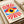 May include: Framed vintage-style Bauhaus poster with geometric eye design featuring radiating red sunburst rays, blue triangular shapes, and central yellow iris with dark blue pupil and white highlight. The minimalist artwork has cream background with "BAUHAUS 1919-1933 SCHOOL OF ARTS & CRAFTS" text below. Frame sits on white surface next to rolled white papers, showing warm natural lighting and clean modern styling.