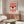 May include: Colorful Bauhaus-style poster with red sunburst rays, central eye design in blue, yellow and white, and "School of Arts & Crafts" text, displayed above wooden sideboard with white ceramic lamp and sculptural vase in minimalist living room with cream chair and glass coffee table
