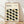 May include: Framed poster with cream background featuring geometric pattern of interlocking leaf or petal shapes in black, olive green, and muted yellow-green. Text reads "BAUHAUS Modernism, minimalism & abstract arts 1919-1933" and "SCHOOL OF ARCHITECTURE WEIMAR, DESSAU, BERLIN." Natural wood frame leans against white wall on light wooden floor with soft natural lighting casting shadows.