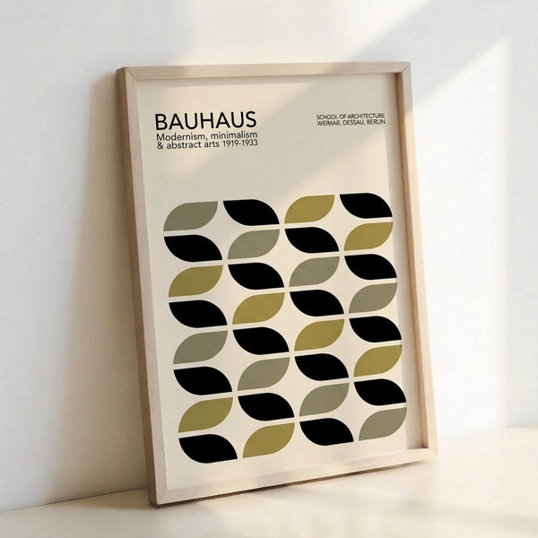 May include: Framed poster with light wood frame leaning against white wall. Print features "BAUHAUS" text at top with "Modernism, minimalism & abstract arts 1919-1933" and "School of Architecture Weimar, Dessau, Berlin" below. Main design shows repeating pattern of leaf-like oval shapes in black, olive green, and muted yellow-green arranged in flowing rows on cream background.