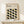 May include: Framed poster displaying geometric pattern of interlocking curved shapes in black, olive green, and sage green on cream background, with "BAUHAUS" text at top. Natural wood frame sits on light wooden surface beside small wrapped gift with twine and dried botanicals against neutral wall.
