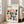 May include: Framed Bauhaus-inspired poster with colorful geometric shapes in a grid pattern, featuring semicircles and quarter-circles in navy, orange, pink, teal, yellow, and purple on cream background. Shows black text reading "BAUHAUS Modernism, minimalism & abstract arts 1919-1933" and "School of Architecture Weimar, Dessau, Berlin." Light wood frame leaning against white wall next to beige sofa in bright, modern living room with hardwood floors.