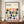 May include: Framed Bauhaus poster with colorful geometric semicircle pattern in navy, teal, orange, pink, yellow and purple on cream background, displayed on wooden sideboard next to white ceramic vase and books in elegant room with white wainscoting walls.