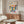 May include: Framed Bauhaus poster with colorful geometric half-circle pattern in yellow, pink, orange, navy, and teal displayed above wooden sideboard. Modern living room setting with white curved chair, glass oval coffee table, and brass floor lamp. Clean minimalist interior with white walls and natural lighting.