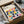 May include: Framed Bauhaus poster with colorful geometric leaf pattern in pink, blue, yellow, orange, and green shapes on cream background, shown being unboxed from cardboard packaging with protective wrapping and wooden frame corners visible on white surface.