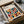 May include: Framed modernist abstract art print featuring overlapping semicircles in vibrant colors including teal, orange, red, olive green, and coral arranged in a geometric grid pattern. The cream-colored poster displays "BAUHAUS" text at top with "Modernism Minimalism & abstract arts 1919-1933" subtitle. Black frame sits in cardboard shipping box with brown paper wrapping and tissue paper on white surface.