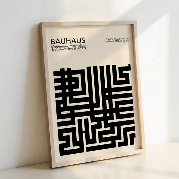 Framed black and white Bauhaus poster with geometric maze-like pattern in natural wood frame, leaning against white wall. Design features bold black angular lines forming an abstract geometric composition on cream background, with "BAUHAUS" text and "School of Architecture Weimar, Dessau, Berlin" at top.