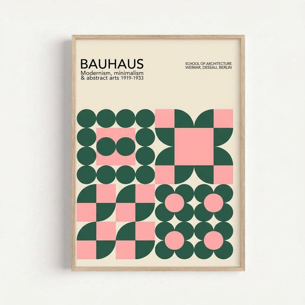 A framed poster with cream background featuring geometric patterns in forest green and coral pink. The design shows four distinct sections: circles arranged in rectangular borders, quarter-circles forming checkerboard patterns, and flower-like motifs made from overlapping circles. Bold black text at top reads "BAUHAUS" with smaller text about modernism, minimalism and abstract arts 1919-1933, plus school locations. Natural wood frame against white wall.