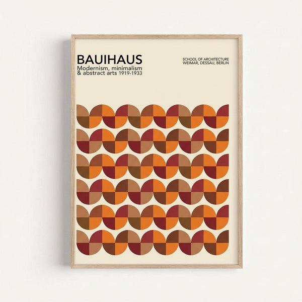 Framed geometric poster with warm autumn colors featuring rows of circles divided into quarters in shades of orange, burgundy, brown, and rust red against a cream background. The minimalist design displays "BAUHAUS" text at top with subtitle about modernism and abstract arts from 1919-1933, plus "School of Architecture" details. Light wood frame hangs on white wall, showing Bauhaus-inspired mathematical pattern with clean lines and earthy color palette.