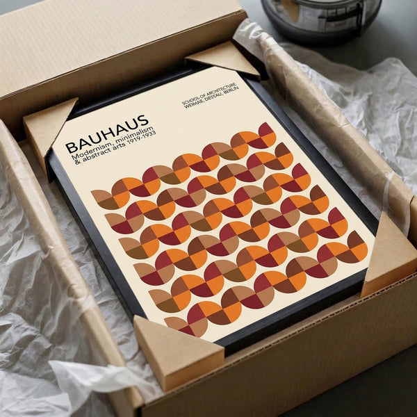 May include: Framed Bauhaus poster with geometric pattern of overlapping circles in warm autumn colors - orange, burgundy, brown, and tan - displayed in black frame, nestled in cardboard shipping box with protective tissue paper wrapping