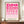 May include: Framed geometric poster with pink gradient circles and semicircles arranged in a grid pattern, displayed on wooden sideboard beside white ceramic vase and stacked books. Features "BAUHAUS 1919-1933 SCHOOL OF ARTS & CRAFTS" text at bottom. Wood frame against cream wall with decorative molding in minimalist interior setting.