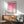 May include: Framed pink geometric art print hanging above mid-century modern wooden sideboard with white ceramic lamp. Sage green upholstered armchair with wooden frame sits nearby. Sunlight creates shadows on white wall. Print features grid pattern of pink circles and semicircles in various shades from bright fuchsia to pale pink on cream background.