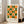May include: Framed geometric art print with orange and green circles and semicircles arranged in a grid pattern on cream background, displayed in light wood frame leaning against white wall next to beige upholstered sofa in bright living room with large windows and hardwood floors.