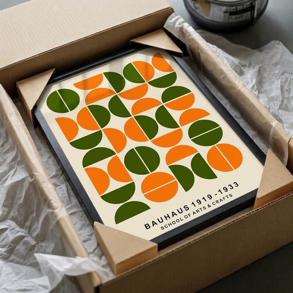 May include: Framed geometric art print with repeating pattern of orange and green half-circles arranged in a grid on cream background. Black frame nestled in cardboard shipping box with protective tissue paper wrapping. Mid-century modern Bauhaus-inspired design with clean lines and bold color contrast.