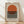 May include: Framed geometric poster featuring a large orange circle above horizontal black stripes on cream background, displayed in light wood frame leaning against white wall on wooden floor with natural lighting creating soft shadows