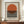 May include: Framed minimalist poster with orange semicircle above horizontal black stripes on cream background, displayed on wooden sideboard next to white ceramic vase and books in elegant room with white paneled walls and warm lighting.
