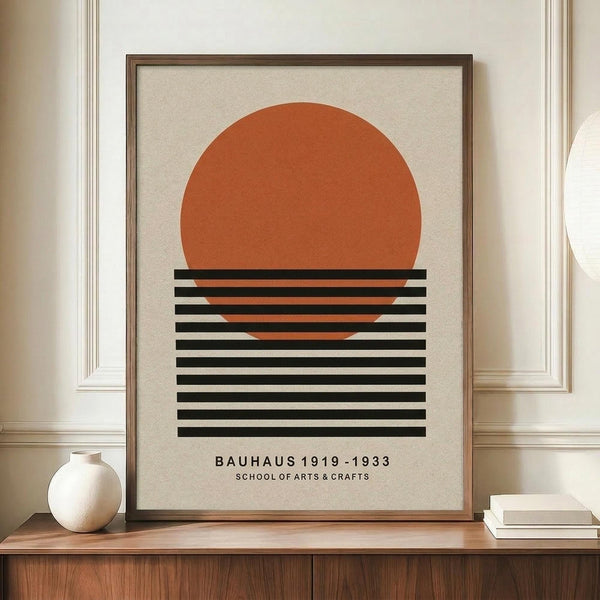 May include: Framed minimalist poster with orange semicircle above horizontal black stripes on cream background, displayed on wooden sideboard next to white ceramic vase and books in elegant room with white paneled walls and warm lighting.