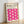 May include: A framed poster leaning against a white wall on light wooden flooring. The print features bold pink wavy shapes arranged in a grid pattern on cream background, with black text reading "BAUHAUS Modernism, minimalism & abstract arts 1919-1933" and "SCHOOL OF ARCHITECTURE WEIMAR, DESSAU, BERLIN" at the top. Natural wood frame with visible grain texture.