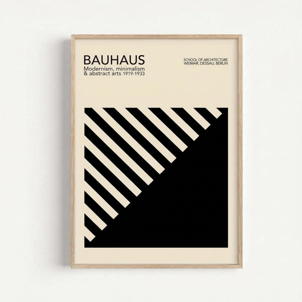 May include: Framed Bauhaus poster with geometric black and cream design featuring diagonal stripes forming an angular pattern. Modern minimalist artwork in light wood frame hanging on white wall. Clean typography at top references the design school's history and locations.