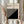 May include: Hands holding a framed minimalist poster with black and white diagonal stripes forming geometric patterns. The print features "BAUHAUS" text and "Modernism, minimalism & abstract arts 1919-1933" with "School of Architecture Weimar, Dessau, Berlin" in smaller text. Light wood frame against cream curtains with dried pampas grass visible on the left side.