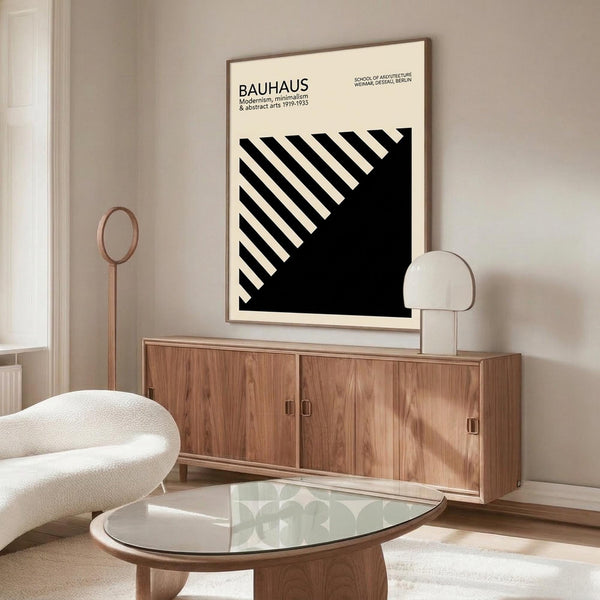 May include: Black and white Bauhaus poster with diagonal stripes in thin wooden frame, displayed above walnut credenza in minimalist living room with cream chair, glass coffee table, and modern lamp. Clean Scandinavian-style interior with neutral walls and natural lighting.